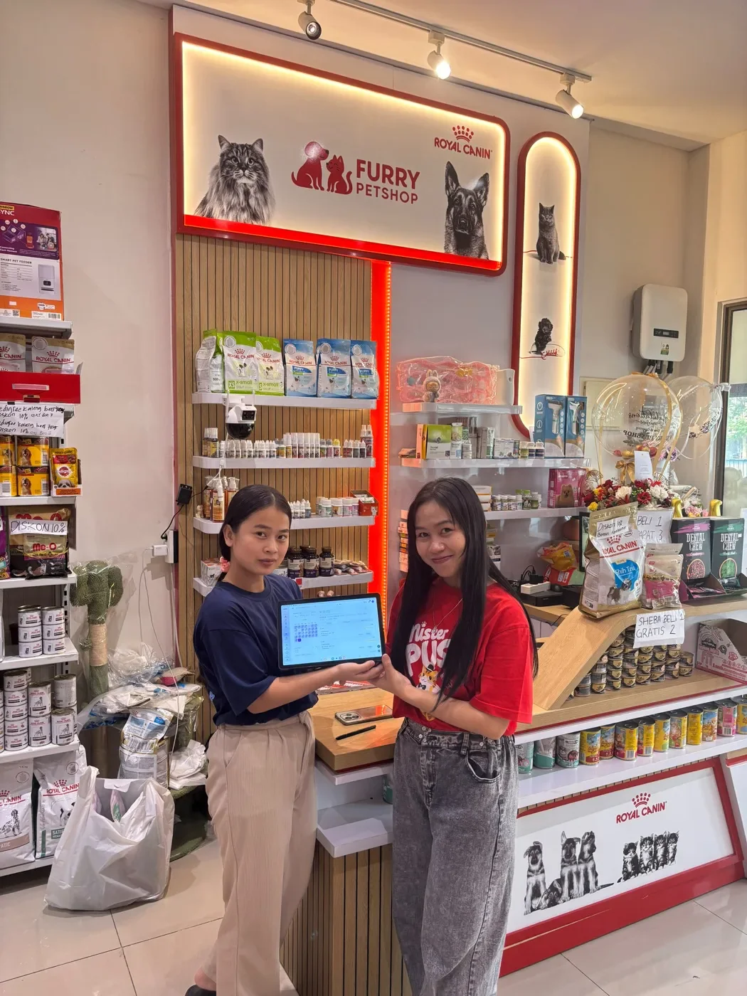 Dua orang menunjukkan tablet dengan tampilan PAWSI di Furry Petshop.