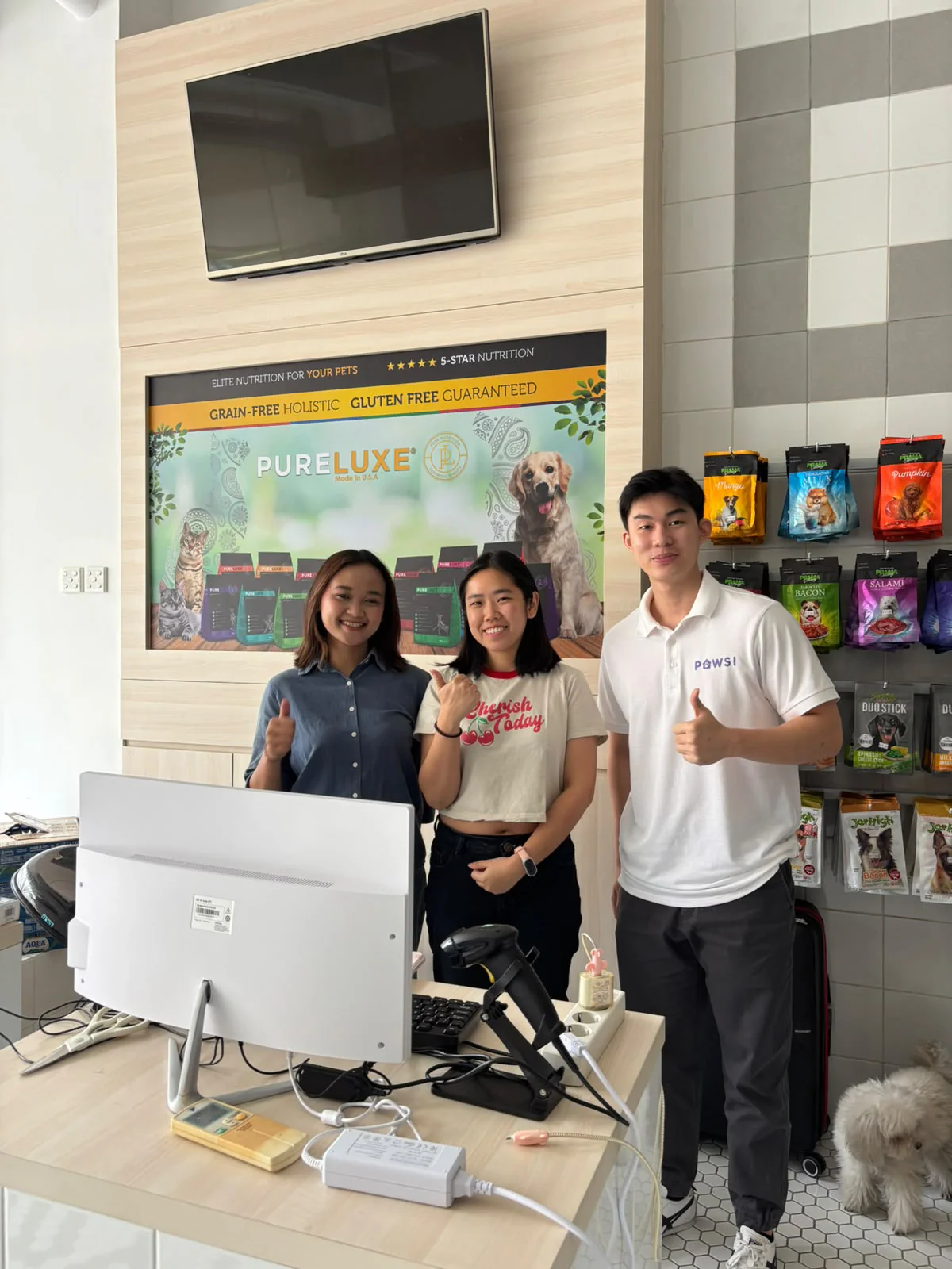 Three people at the Giowo Petshop counter, one wearing a PAWSI shirt.