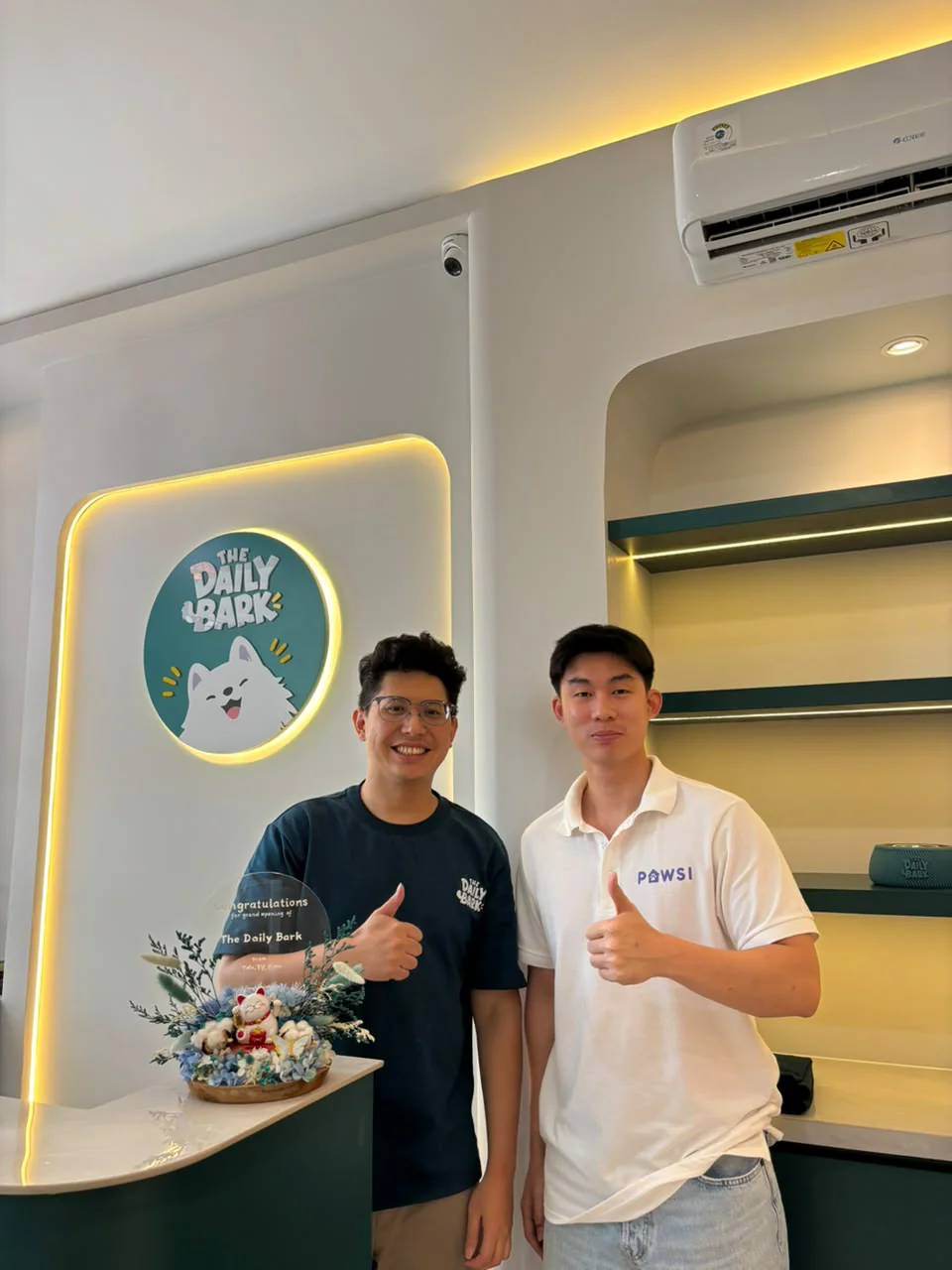 Dua orang di meja The Daily Bark, salah satunya mengenakan kaus PAWSI.